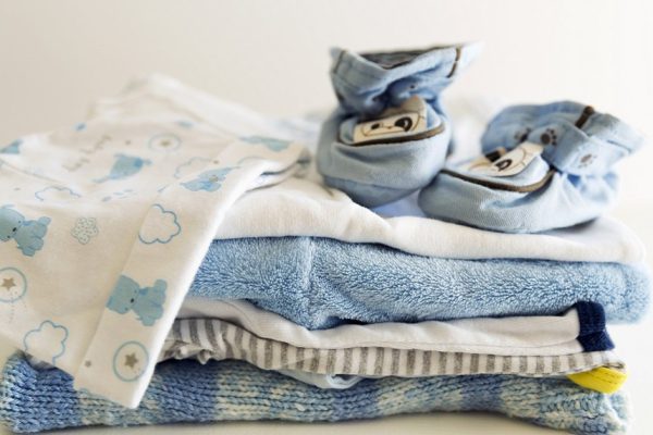 Set of things for a newborn baby boy. Maternal concept. Baby clothes in pile and tiny baby shoes and hat