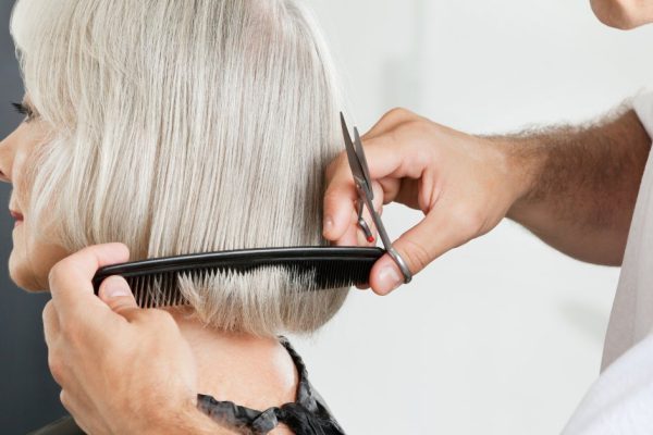 Closeup of male hairstylist measuring hair length before haircut in parlor