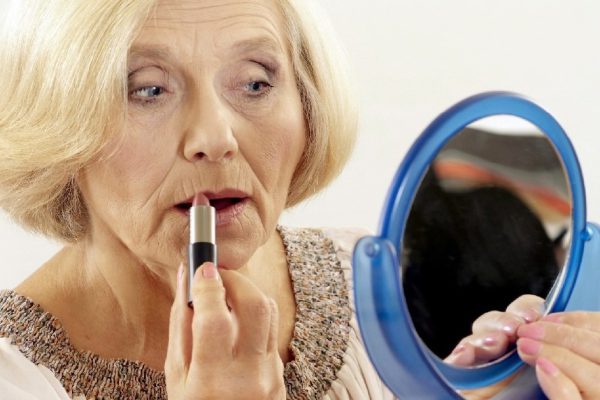 mature woman makes her makeup over light background