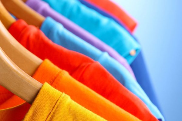 Lots of T-shirts on hangers on blue background