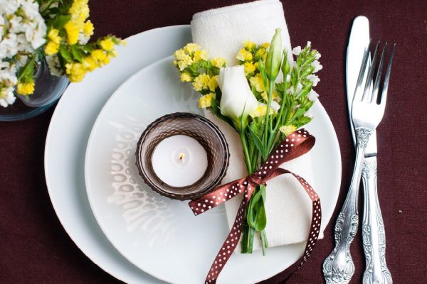 Festive table setting and decoration with fresh flowers in brown and yellow