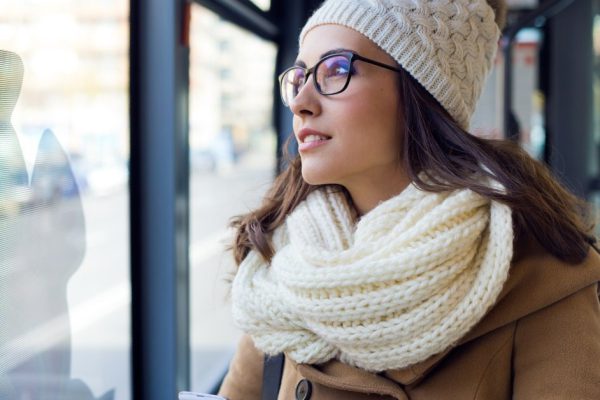 Outdoor portrait of young beautiful woman using her mobile phone on a bus.