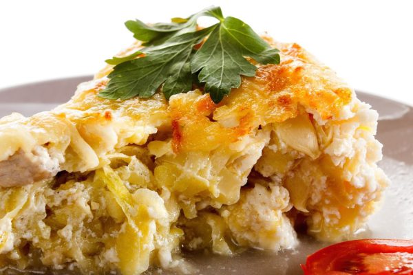 Baked squash with meat, cherry tomatoes and herbs in a glass pot.  Closeup studio shot