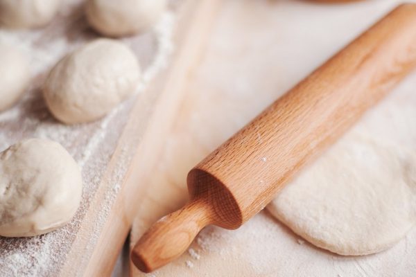 wooden rolling-pin and homemade dough ready for cooking pies