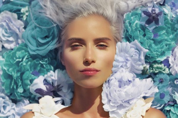 Beautiful blonde young woman lying in flowers