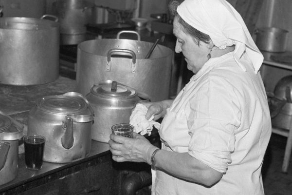 Moscow, USSR - November 23, 1989: Canteen in the Ministry of the Automotive Industry of the USSR. Woman emloyee of the canteen makes tea in large metal tea pot in the cooking area of the canteen.
