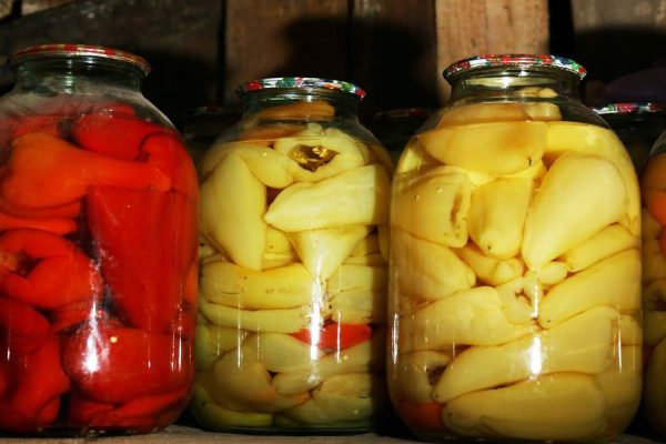 Home preserved peppers in glass jars in cellar, closeup