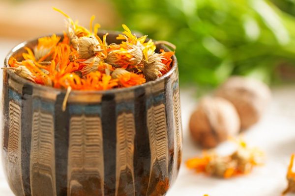 Dried marigold flowers in a brown clay pot.