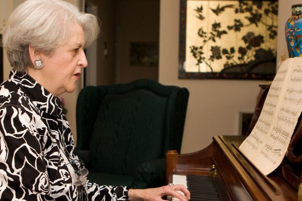 Senior adult woman in active retirement living plays the piano in her home.