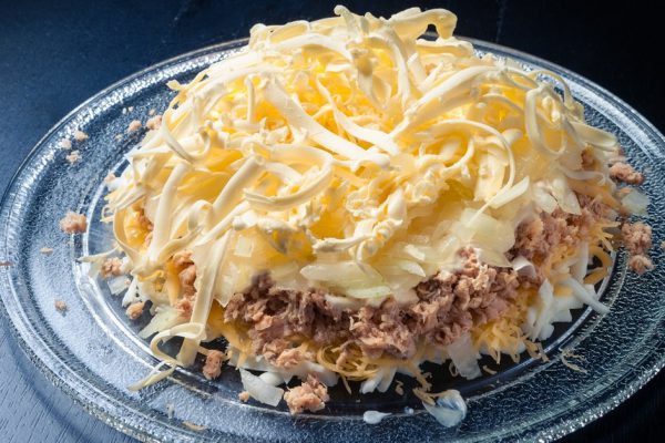 fish salad on glass plate on dark background