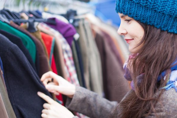 Attractive woman choosing clothes at flea market.
