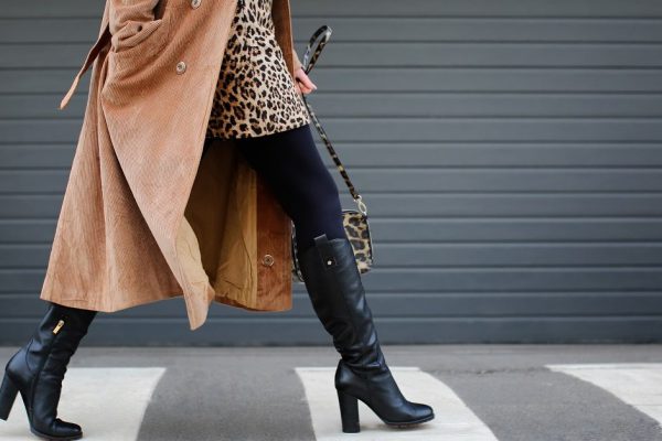 Stylish woman in black shoes walking across the street