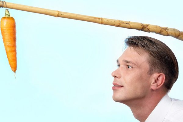 Portrait of businessman looking at fresh carrot on angle