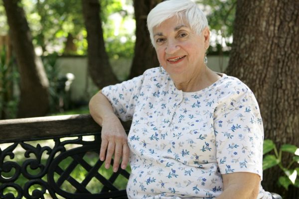 A sweet senior lady relaxing on a park bench.   Room for text.