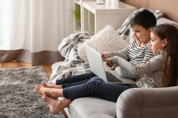 Cute little children with laptop watching cartoons at home