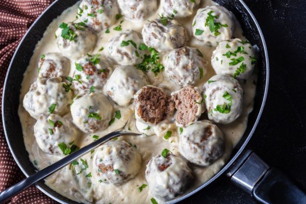 classic Swedish meatballs with creamy sauce and parsley in a skillet on a concrete kitchen table with brown cloth