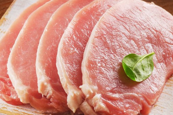 Raw pork chops on wooden cutting board. Selective focus