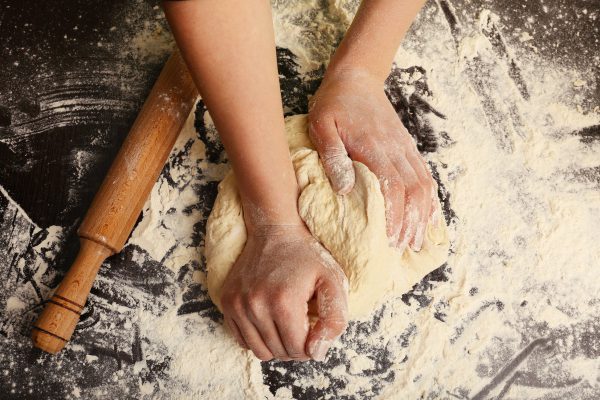 Making dough by female hands on wooden table background