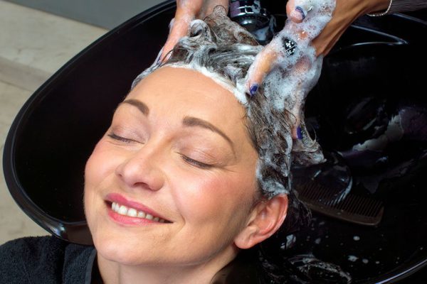 attractive mature woman get her hair washed in salon
