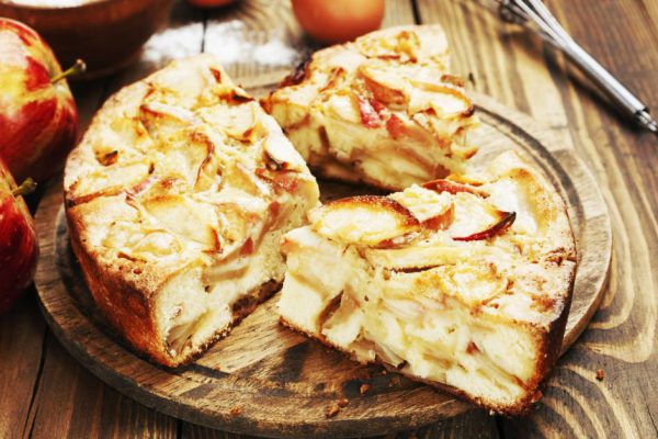 Apple pie and red apples on a wooden table