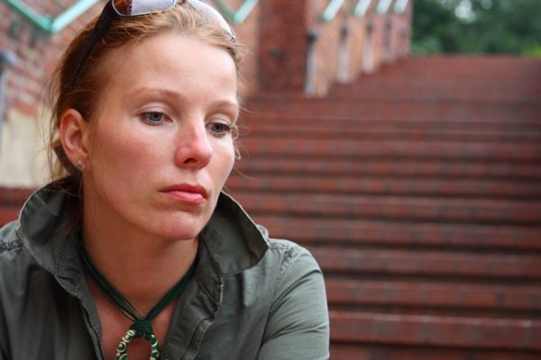 Girl standing alone against a wall outdoor