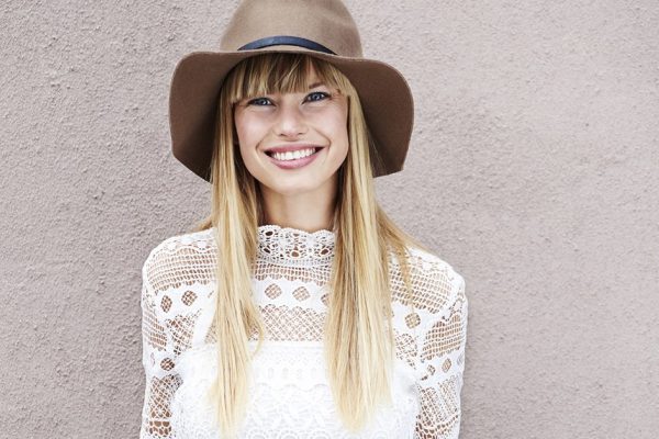 Beautiful young woman in hat smiling at camera
