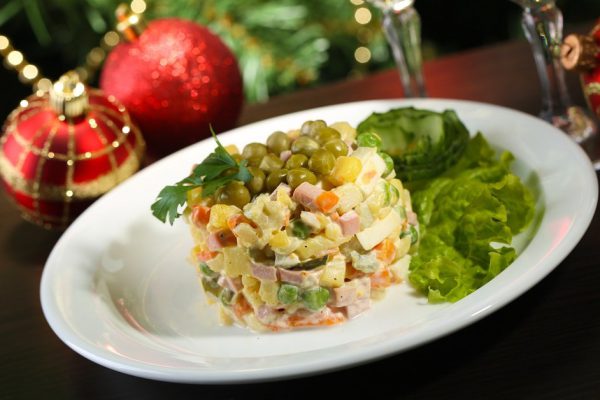 Russian traditional salad Olivier,  on wooden  table, on bright background