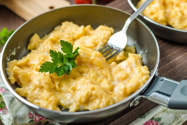 Scrambled eggs with herbs and homemade bread, on two frying pans