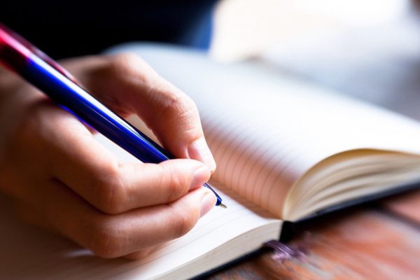 Close-up of hand pen writes in a notebook (blurred)