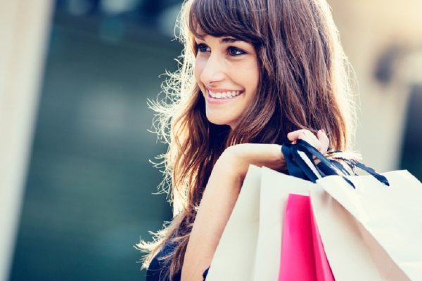 Happy woman holding shopping bags and smiling at the mall