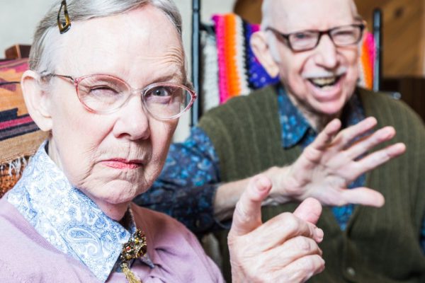 Angry old couple sitting in living room woman pointing