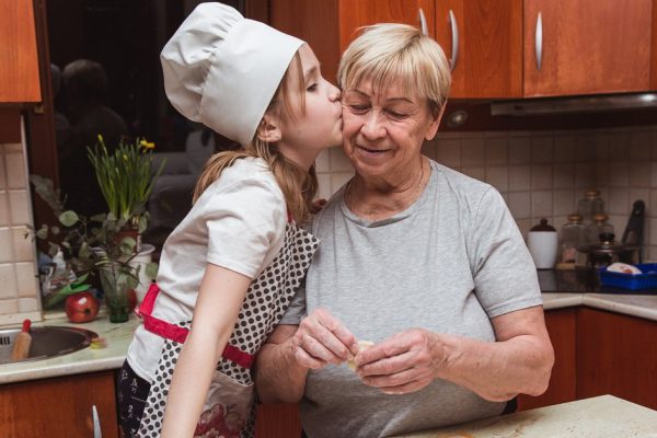 Little girl with grandmother in the kitchen sculpts dumplings for dinner
