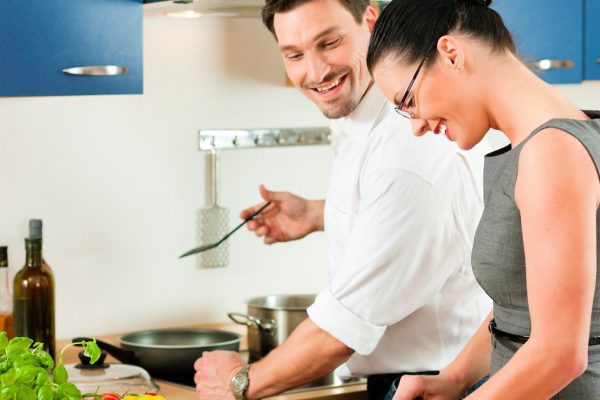 And woman in their kitchen at home preparing vegetables for salad and pasta sauce