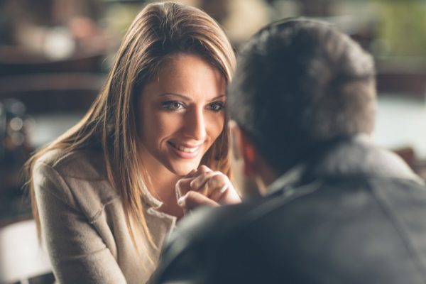 Romantic young couple dating and flirting at the bar, staring at each other's eyes