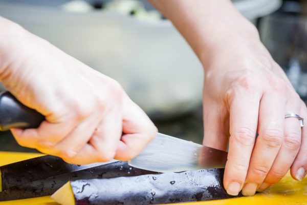 Closeup of womans hands cutting eggplant