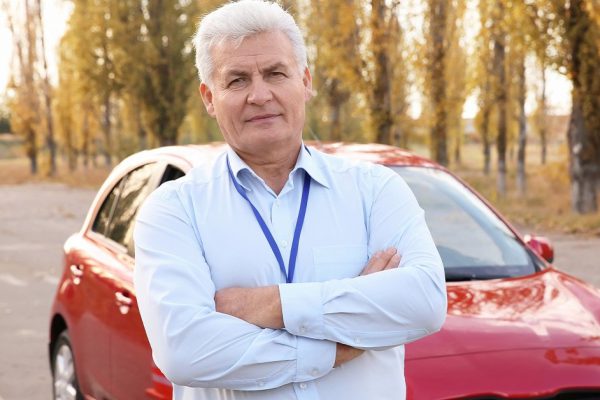 Senior instructor near modern car outdoors. Get driving license