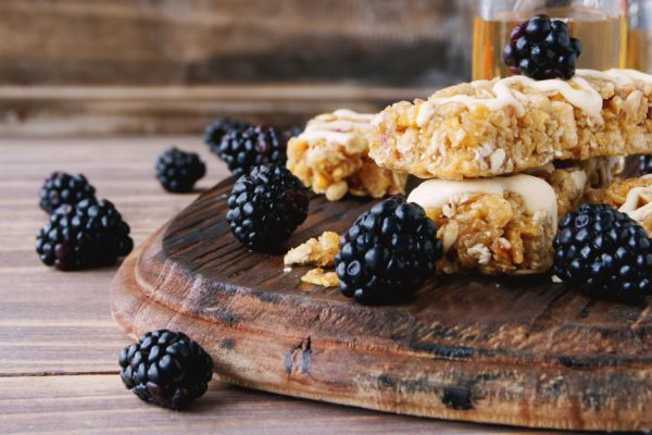 Cookies of cereals with fruit and berries on a wooden table with a jar of honey