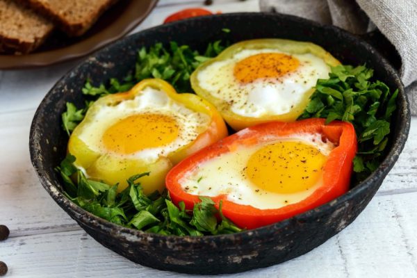 Fried egg in the ring of the bell peppers with herbs and brown bread - light diet breakfast.