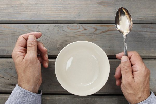 Hungry man waiting for his meal over empty bowl on wooden table.