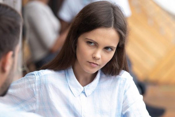 Attractive young doubting woman looking at man in cafe close up, bad first impression, new acquaintance in public place, girlfriend listen to talking about news boyfriend, serious conversation