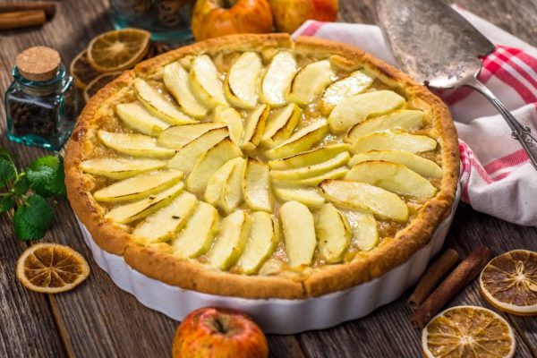 Homemade apple pie and ingredients on a rustic table