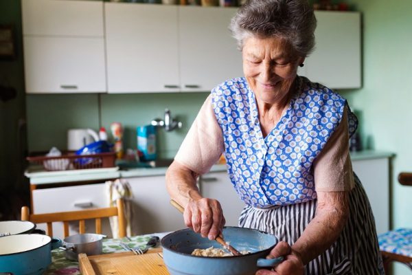 Senior woman baking pies in her home kitchen.  Mixing ingredients.