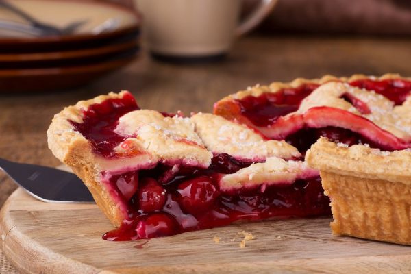Closeup of a slice of cherry pie on a wooden platter