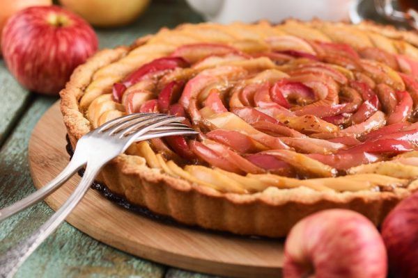 Apple rose tart. Tasty homemade pie served with tea and apples closeup