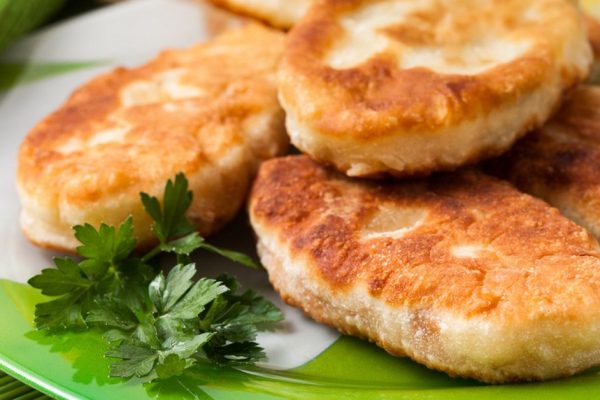 Fried pies on the green dish with sour cream