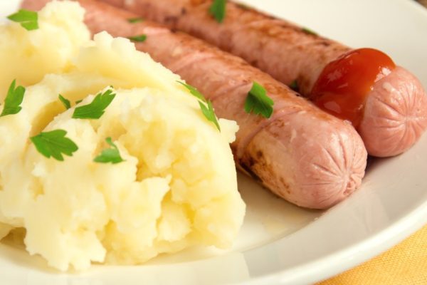 mashed potato  and sausages with parsley and ketchup on white plate
