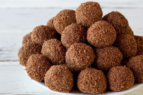 Pile of candies on plate. Brown sweets with crumbs. Simple recipe of chocolate balls. Cocoa and crumbled cookies.