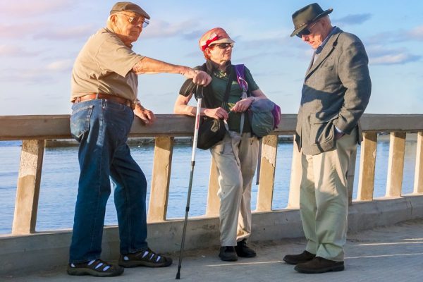 Cefalu, Italy, November 2, 2017: Two elderly men and one woman standing on the waterfront