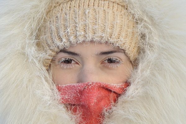 Girl with hoarfrost on the eyes. The white fur coat and hood. Very cold, frost. His face is closed, you can see only the eyes