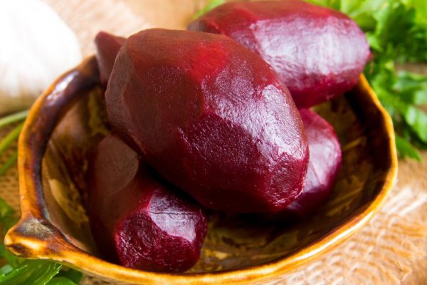Boiled beetroots in bowl with parsley over rustic wooden table. Ingredient of traditional russian cuisine.